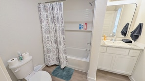 Ein Badezimmer mit Toilette, Dusche, Waschbecken und Spiegel.