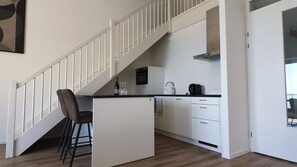 Una cocina moderna con una isla central, armarios blancos y una campana extractora de acero inoxidable.