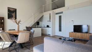 Un espacio habitable moderno con comedor, cocina y una escalera que conduce a un nivel superior.