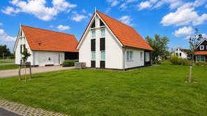 Dos casas blancas con tejados rojos y un césped verde.