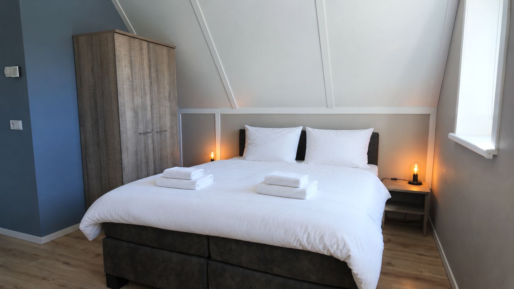 A bedroom with a bed, bedside tables, and a wardrobe.