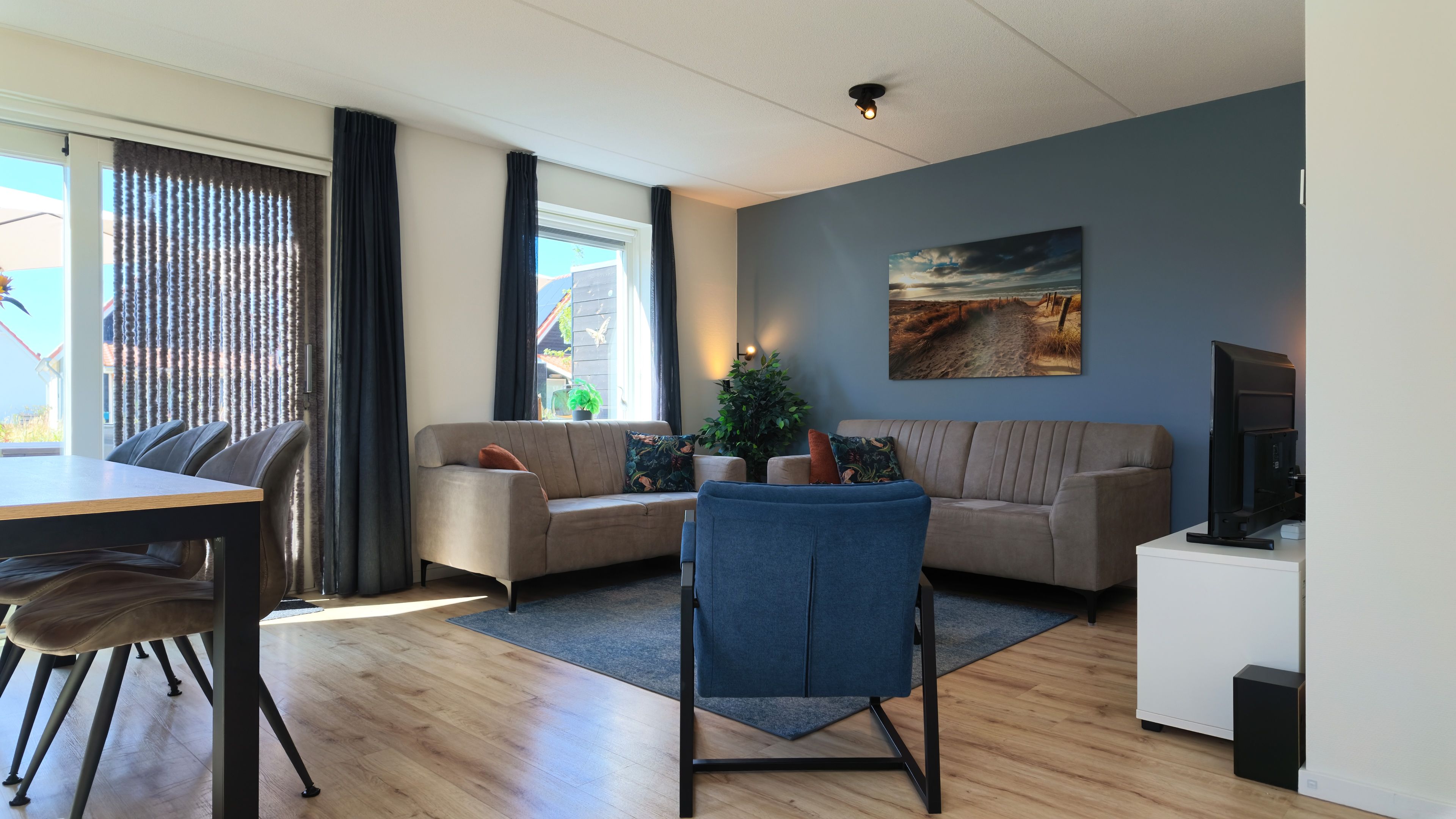 Ein modernes Wohnzimmer mit einer Couch, einem Esstisch und einem Fernseher.