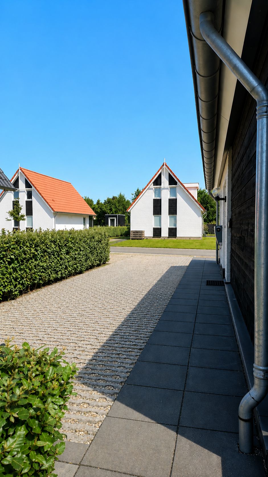 A paved pathway leading to a row of white buildings with red roofs, surrounded by greenery.