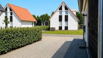 A paved pathway leading to a row of white buildings with red roofs, surrounded by greenery.