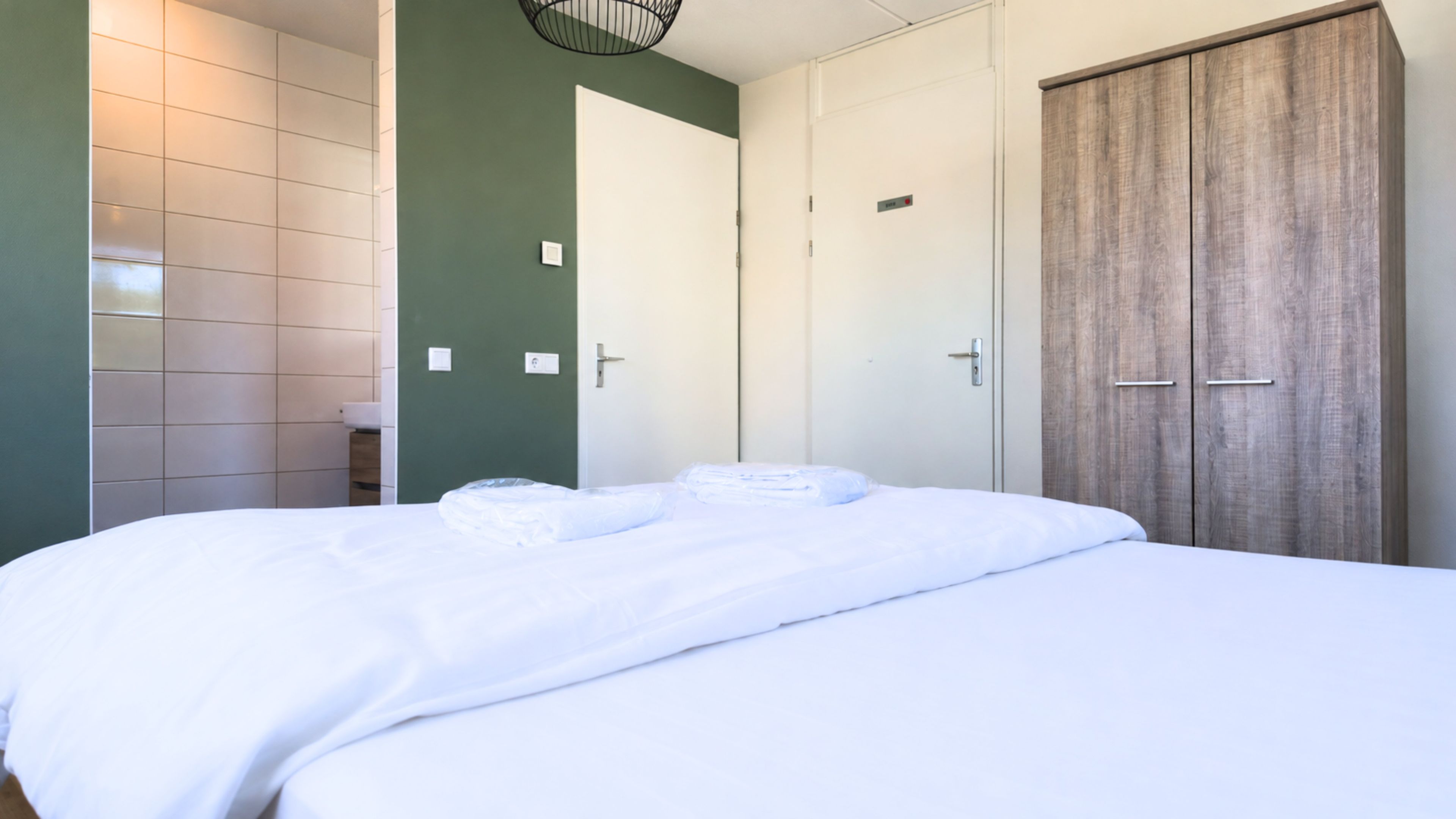 Una camera d'albergo con un letto, un armadio e un bagno.