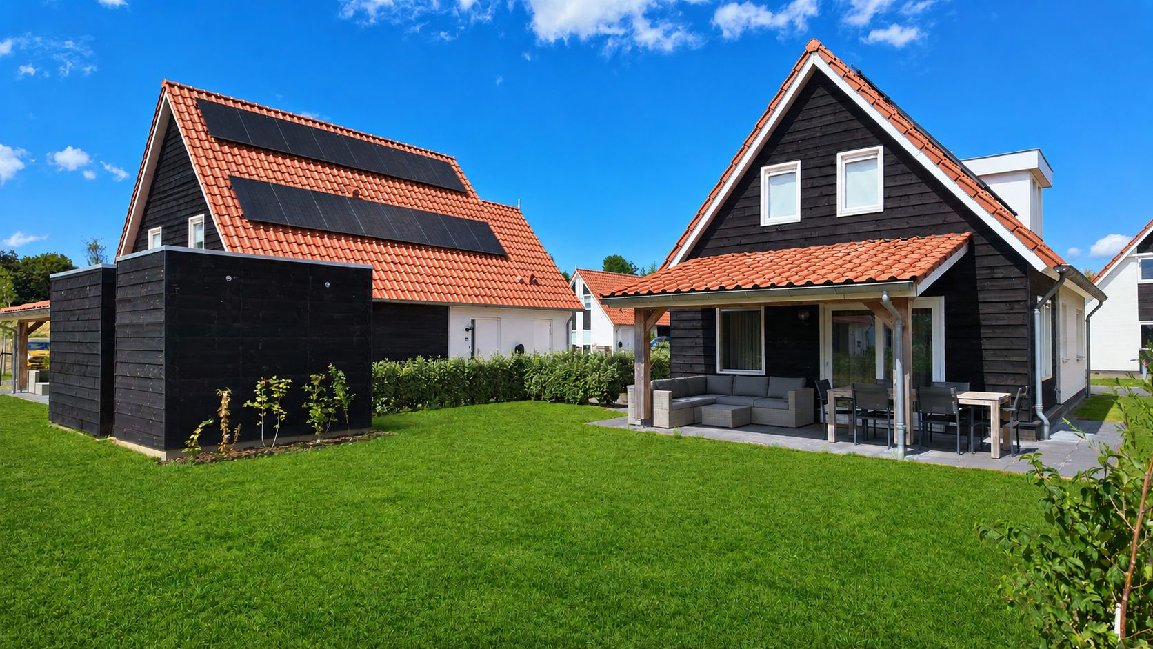 Il s’agit d’une propriété résidentielle dotée d’une pelouse bien entretenue, d’un patio aménagé avec du mobilier d’extérieur, et d’une maison avec un toit recouvert de tuiles rouges et équipée de panneaux solaires.