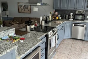 A kitchen with granite countertops, stainless steel appliances, and light blue cabinetry. - Cozy 2-bedroom cabin on the Amite River that sleeps 8 adults (Saint Amant)