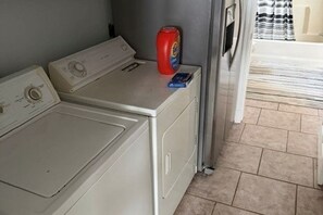 A laundry area with two washing machines and a detergent bottle. - Cozy 2-bedroom cabin on the Amite River that sleeps 8 adults (Saint Amant)