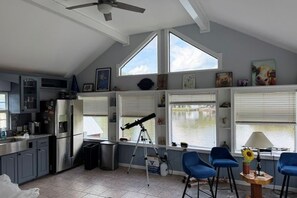 A kitchen with a ceiling fan, a telescope, and a dining area with blue chairs.
