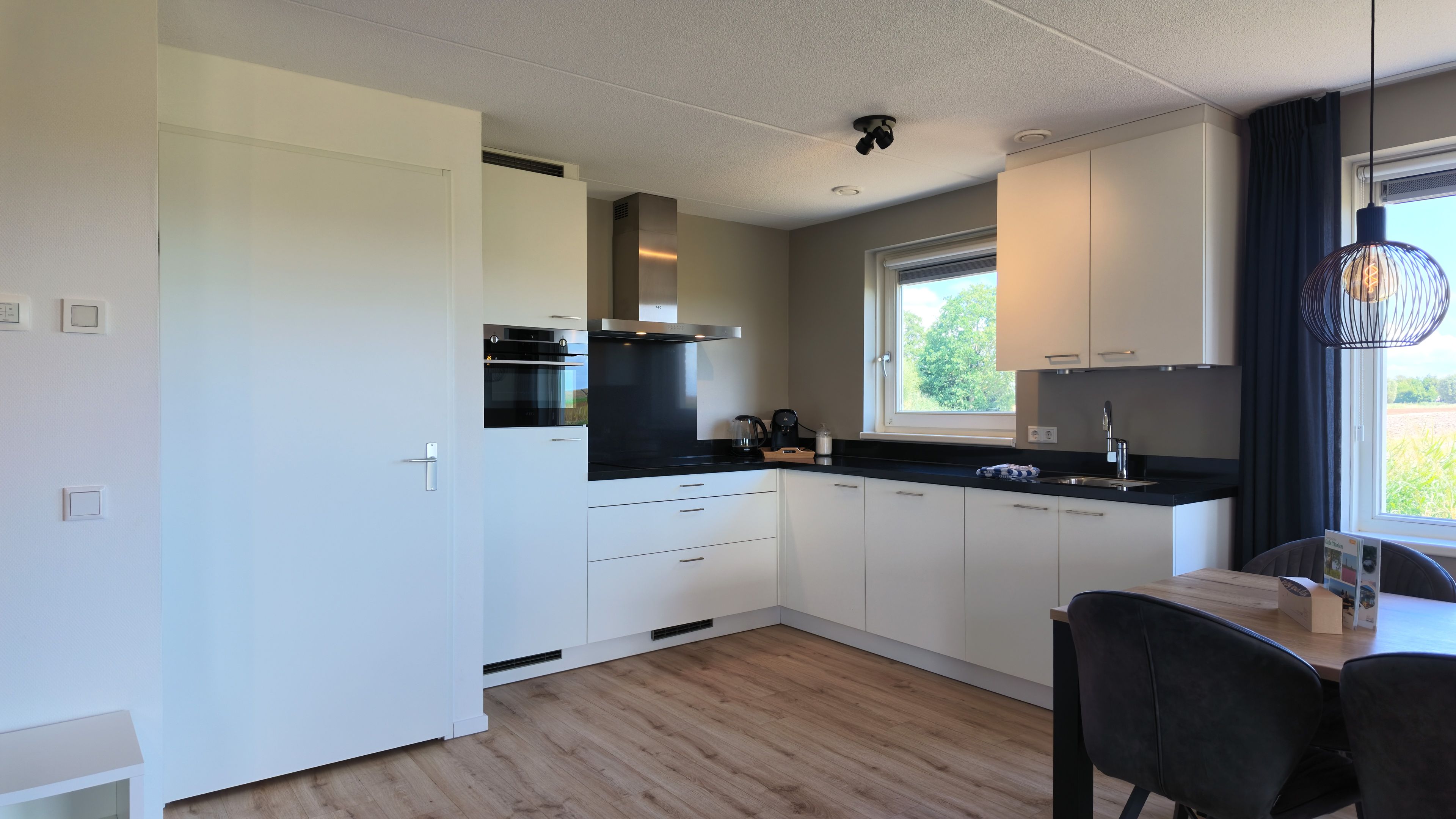 A modern kitchen with white cabinetry, a black countertop, and a window providing natural light.