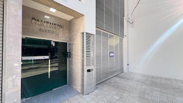 Entrada de um edifício com uma placa indicando 'PANTHEON RESIDENCE' e um portão de segurança.