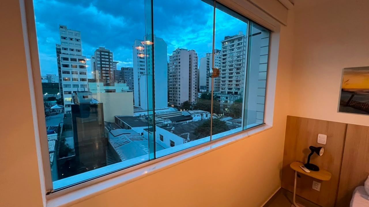 Quarto com uma grande janela e vista para a cidade.