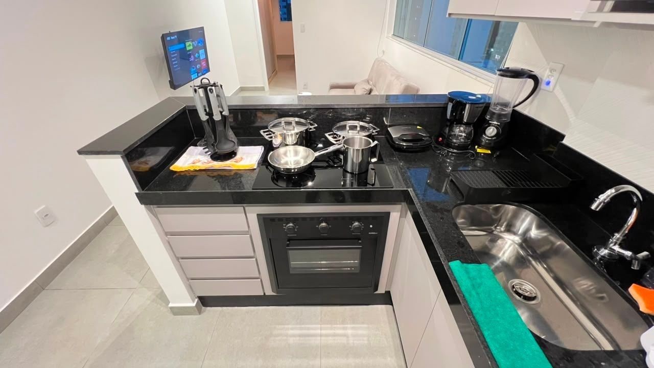 Una cocina compacta con horno integrado, cafetera y lavabo.