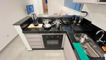 Una cocina compacta con horno integrado, cafetera y lavabo.