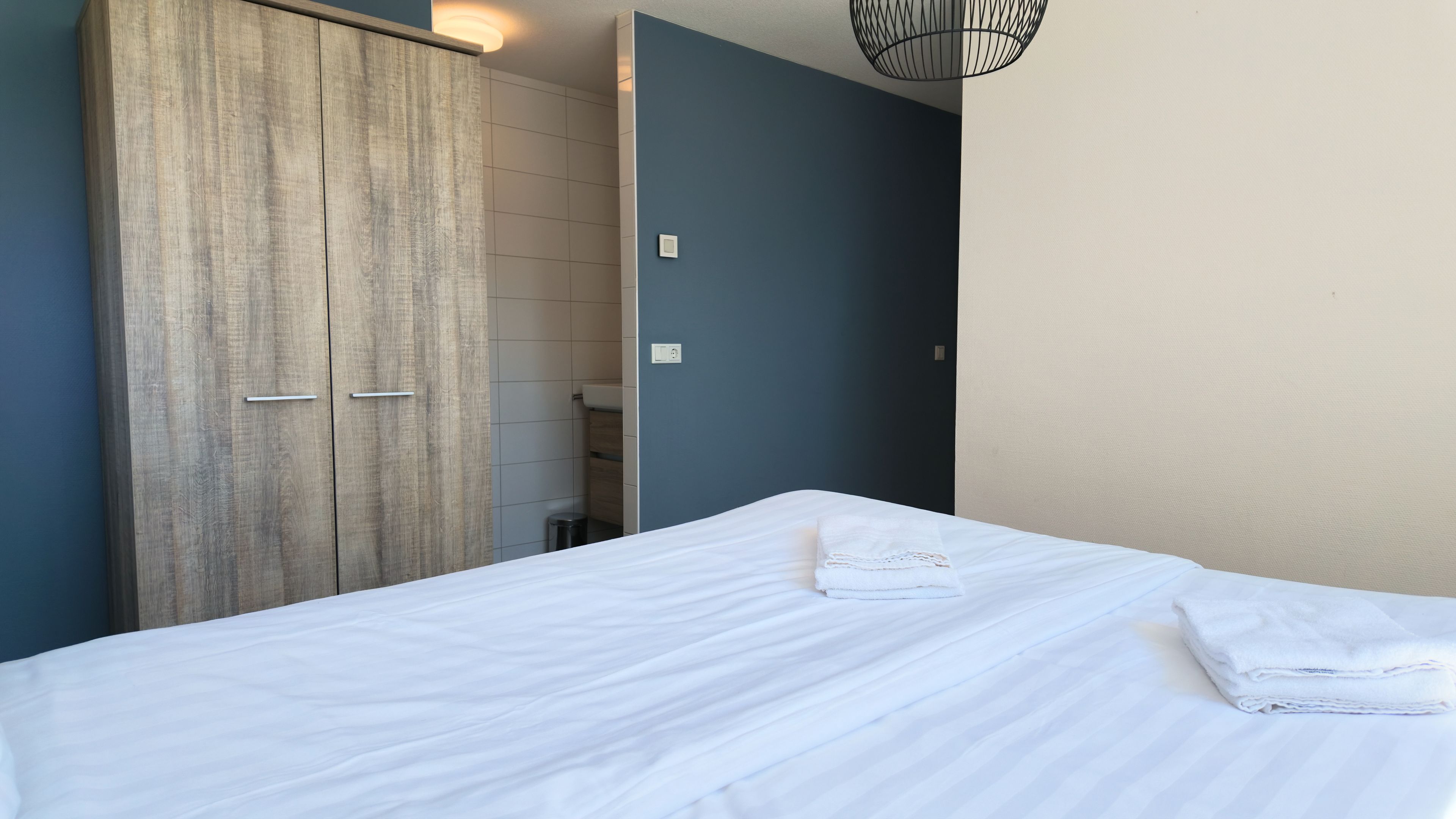 Une chambre d’hôtel avec un lit, une armoire et une salle de bain.
