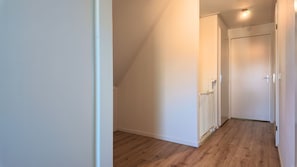 A narrow, well-lit hallway with wooden flooring and white walls, leading to a door at the end. - Looking for a holiday home in Zeeland for 8 people? Discover Villa De Merel, featuring four bedrooms, three bathrooms and a covered terrace. (Scherpenisse)