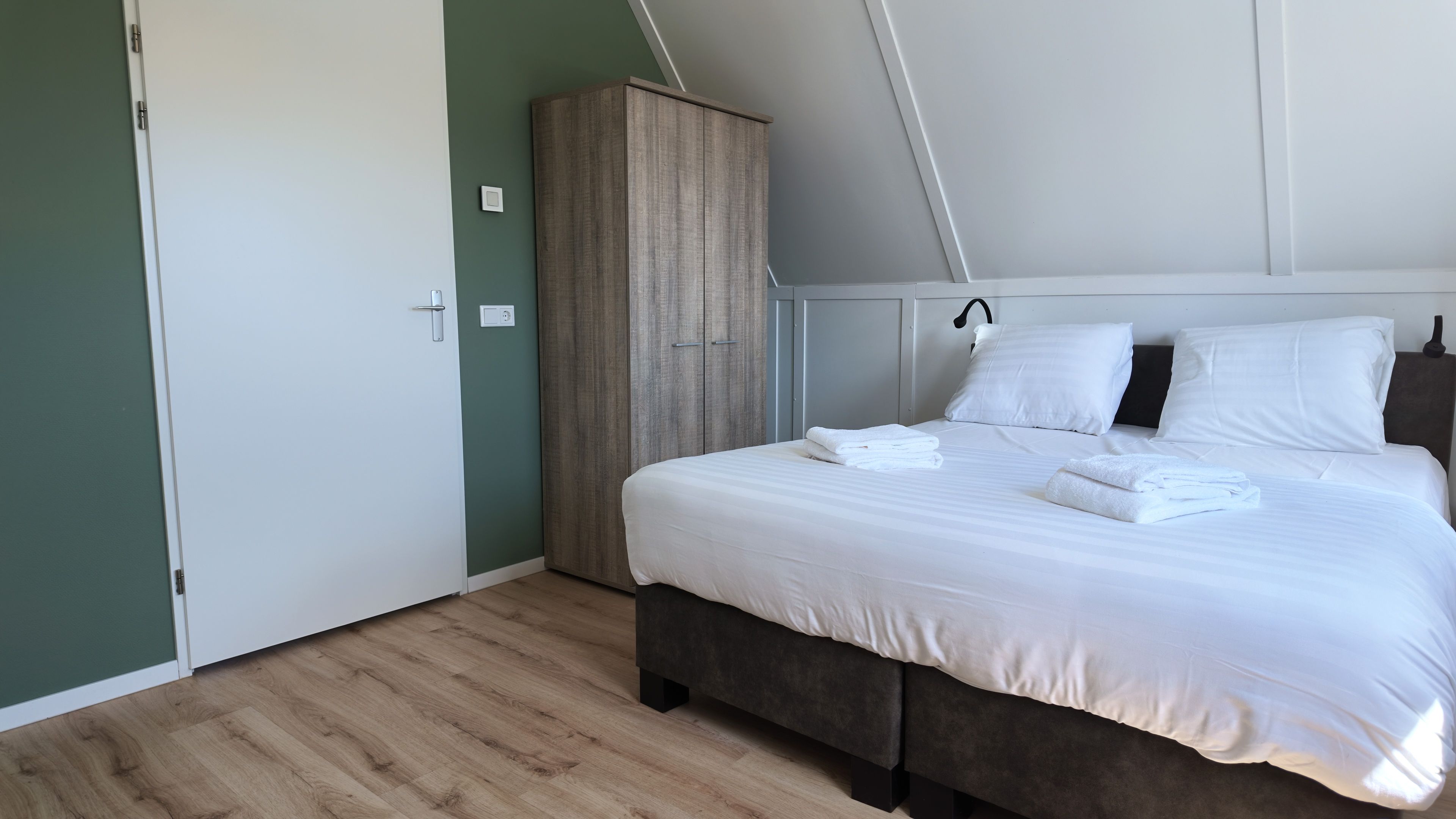 Une chambre à coucher avec un lit, une armoire et une porte.