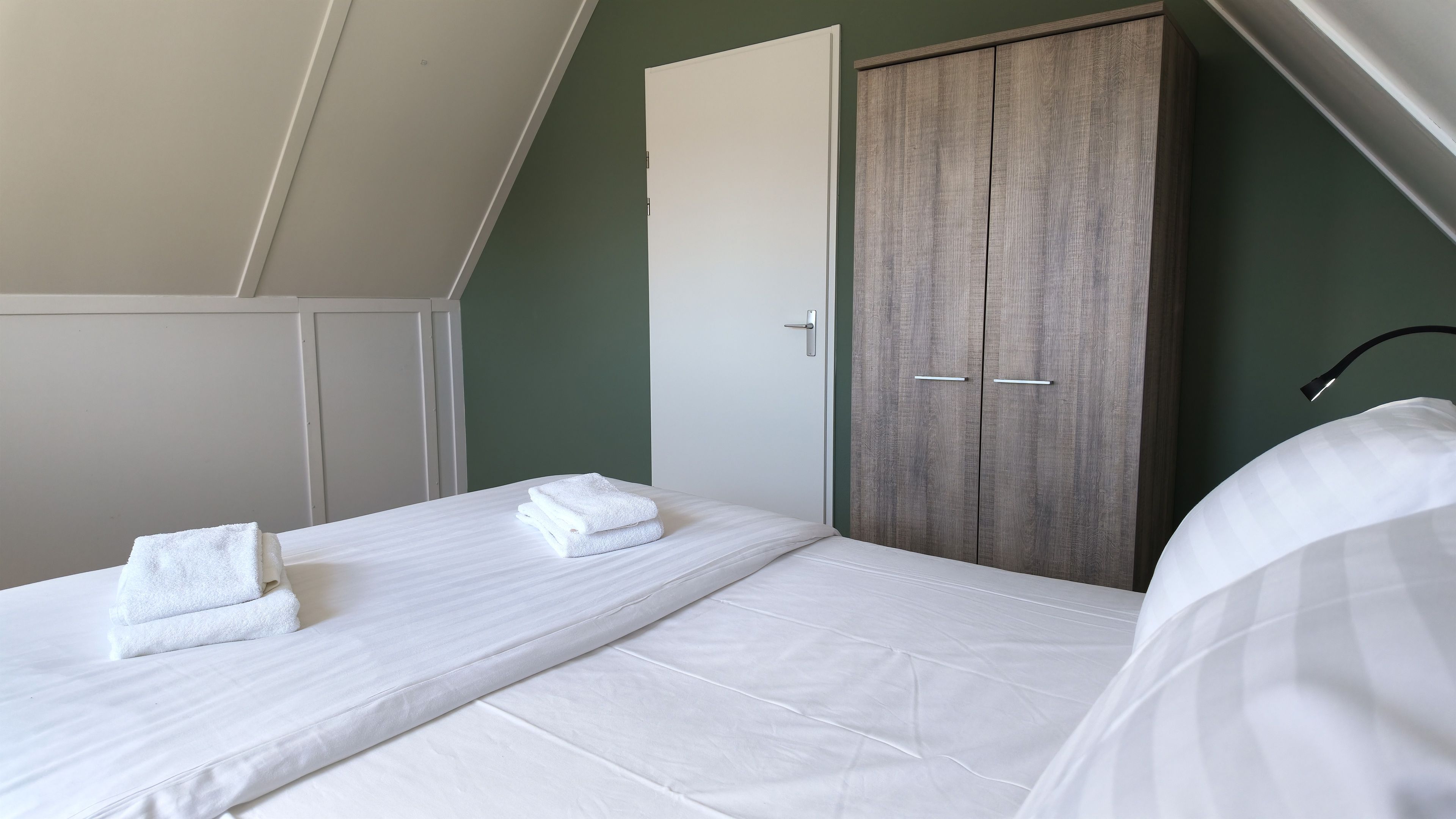 Een slaapkamer met een enkel bed, een kledingkast en een deur.