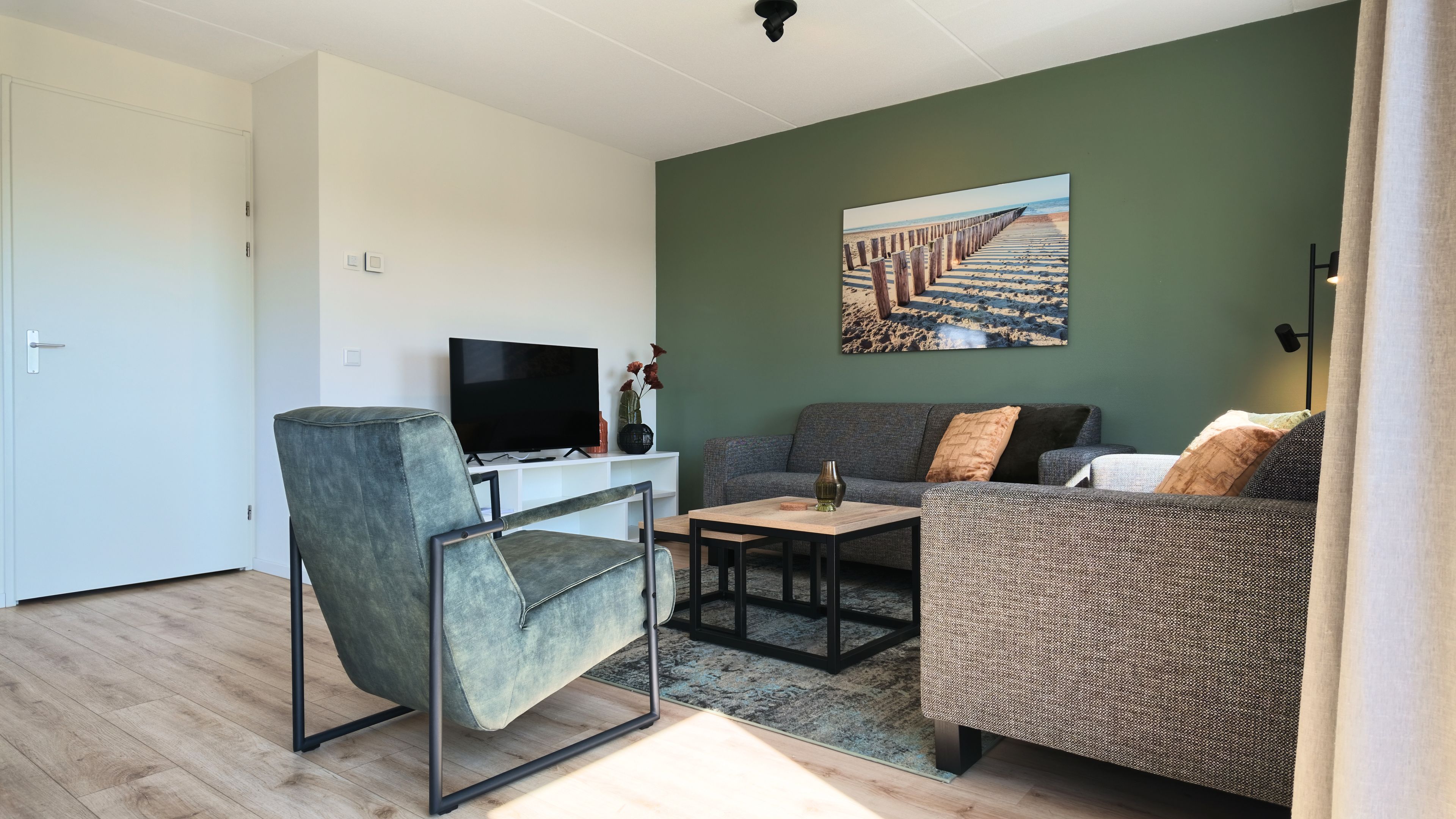 Un salon moderne comprenant un canapé, un fauteuil, une table basse et un téléviseur à écran plat.