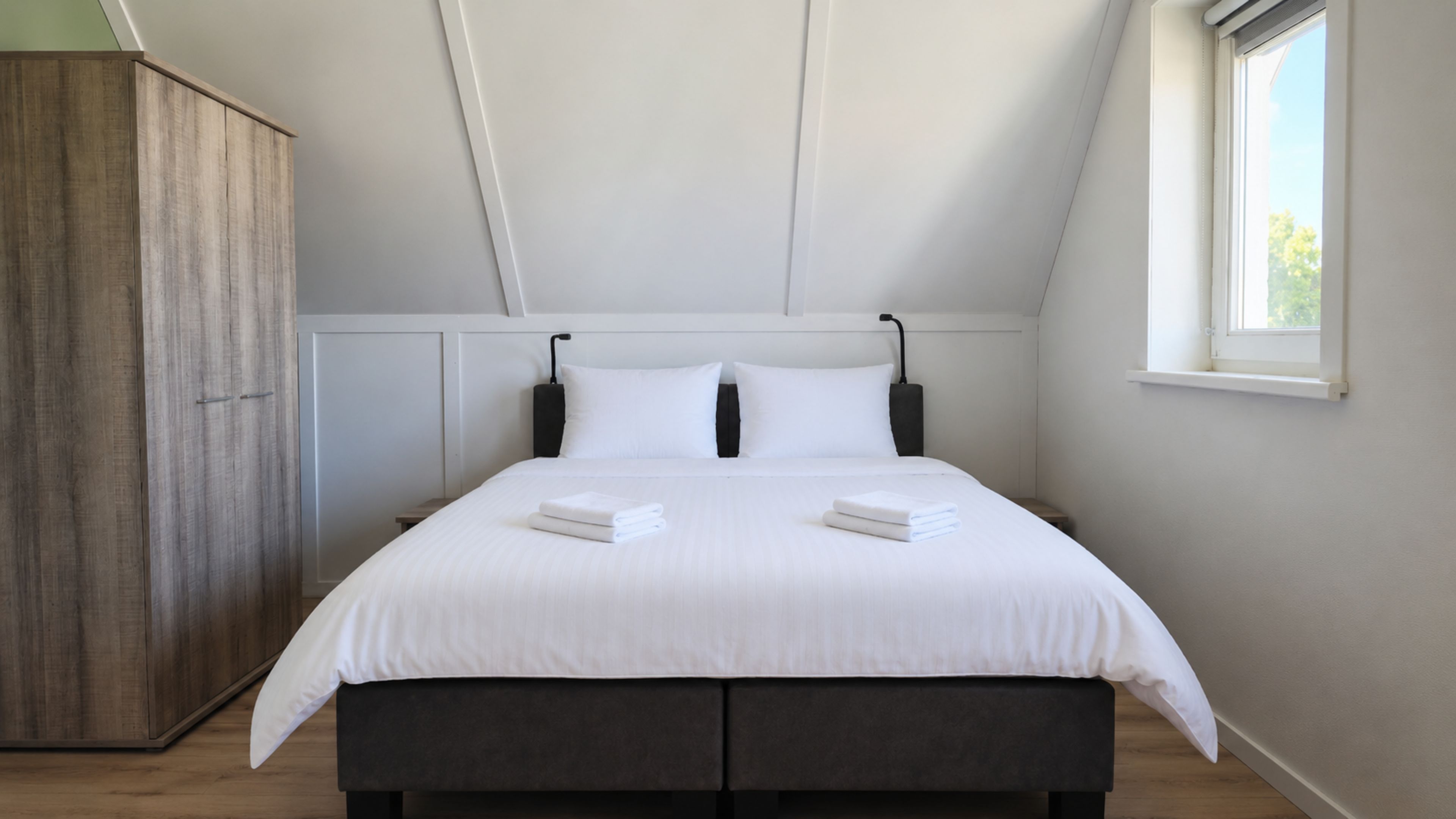Une chambre avec un grand lit, une armoire et une fenêtre.
