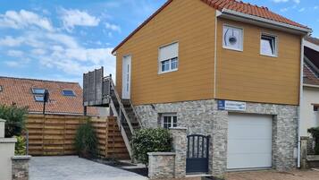 Un immeuble résidentiel à deux étages, doté d’un garage, d’une clôture en bois et d’un mur en pierre.