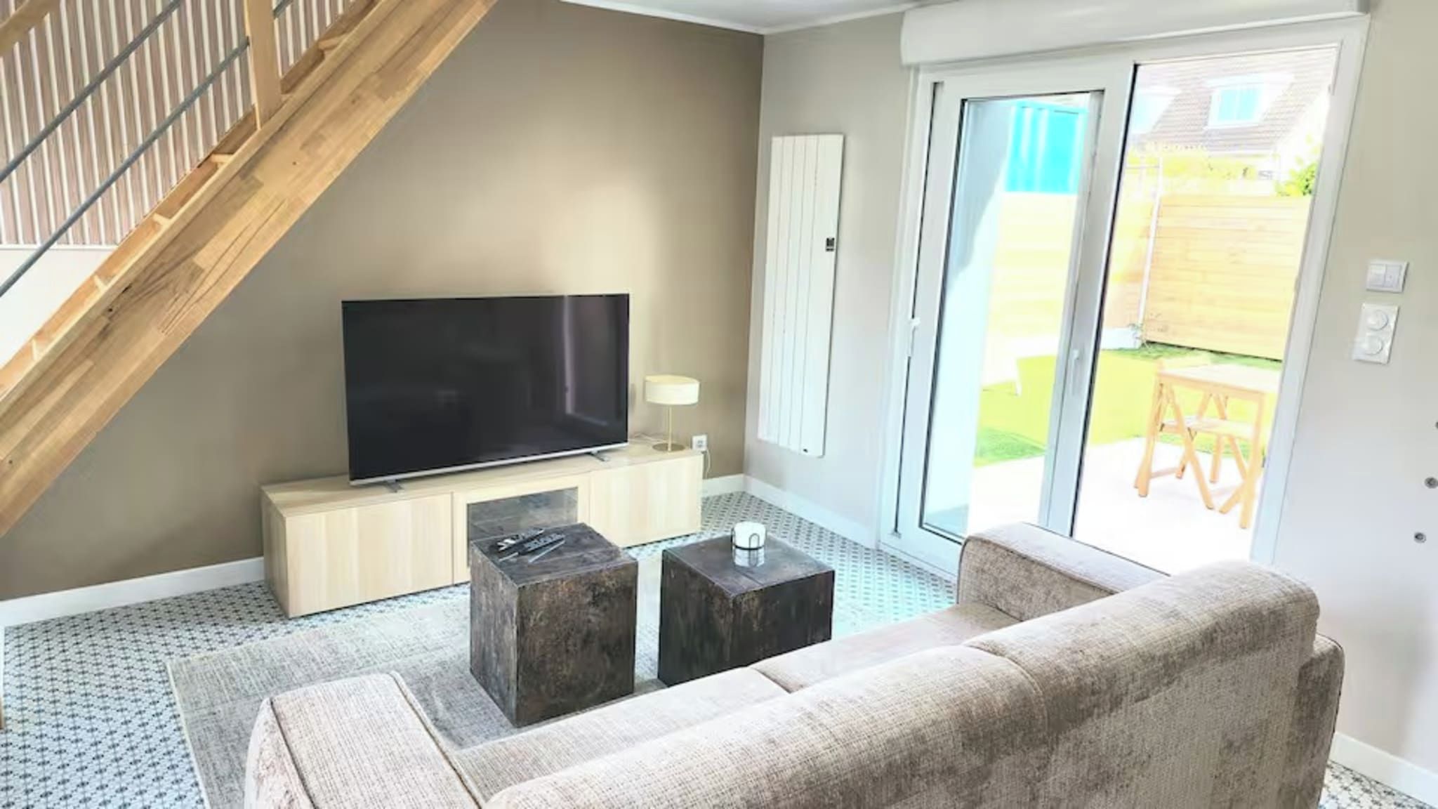 A living room with a TV, sofa, coffee table, and a staircase.