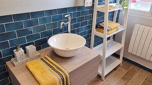 Een badkamer met een wit wastafel, blauwe tegels, een handdoek en een plank met handdoeken.