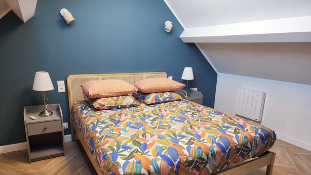 Een slaapkamer met een houten bed, een nachtkastje, een lamp en een stopcontact.