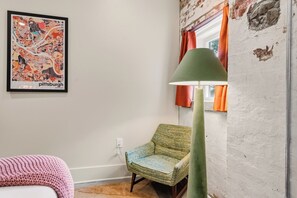 Een kamer met een lijst met een kaart van Pittsburgh, een groene lamp, een geweven stoel en een roze gebreide accessoire.