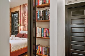 A hotel room with a bed, a bookshelf, and a door. - Dedicated Parking | King Bed | Arcade | Patio (Pittsburgh)