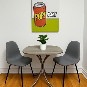 Een eethoek met een ronde tafel, twee stoelen en een potplant.
