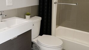 Et moderne badeværelse med vask, toilet og badekar.