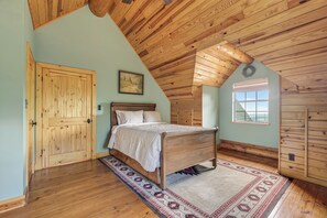 A bedroom with a wooden ceiling, a bed, a wardrobe, and a window.