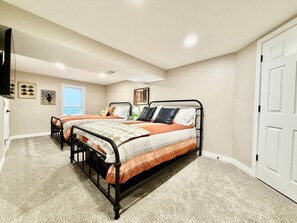 A bedroom with a double bed, a bedside table, a chair, a window, and a door.