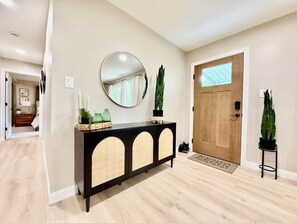 A hallway with a black console table, a round mirror, and a wooden door.