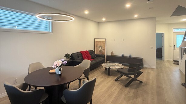 Een moderne woonkamer met een eethoek, een bank en een trap naar een hoger niveau.