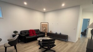 Een moderne woonkamer met een zwarte leren bank, een ronde salontafel en een zwarte fauteuil.