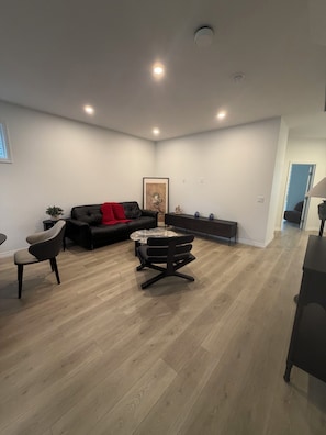 A modern living room with a black leather sofa, a round coffee table, and a black chair.
