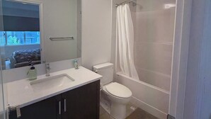 Een badkamer met een wastafel, spiegel, toilet en douche.