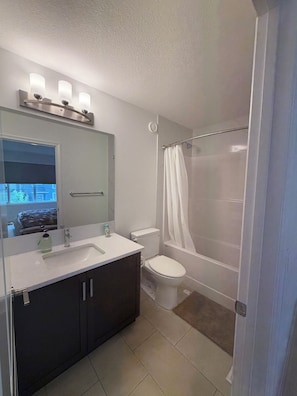 A bathroom with a sink, mirror, toilet, and shower.