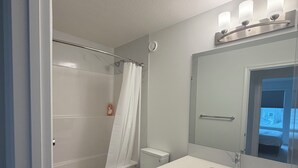 Et badeværelse med brusebad, toilet og håndvask.