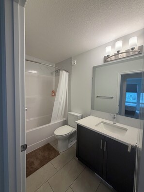 Une salle de bain avec douche, toilettes et lavabo.