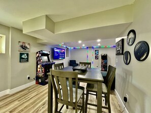 Une pièce comprenant une table à manger, des chaises, un téléviseur et une console de jeux.