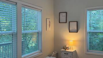Et soveværelse med seng, loftventilator, et natbord med lampe og to billeder i rammer på væggen.