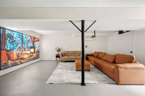 A modern living room with a large flat-screen TV, a sectional sofa, and a minimalist design. - Family Haven | Theater | Game Room | Backyard Fun (Lawrenceville)