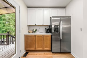 A compact kitchen with white cabinets, a stainless steel refrigerator, and a coffee maker. - Family Haven | Theater | Game Room | Backyard Fun (Lawrenceville)
