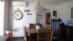 A dining area with a wooden table, chairs, a clock, and a wall-mounted sign. - Vrbo Property (Kristianstad)
