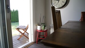 Una stanza con un tavolo da pranzo in legno, uno sgabello rosso e una pianta in vaso.