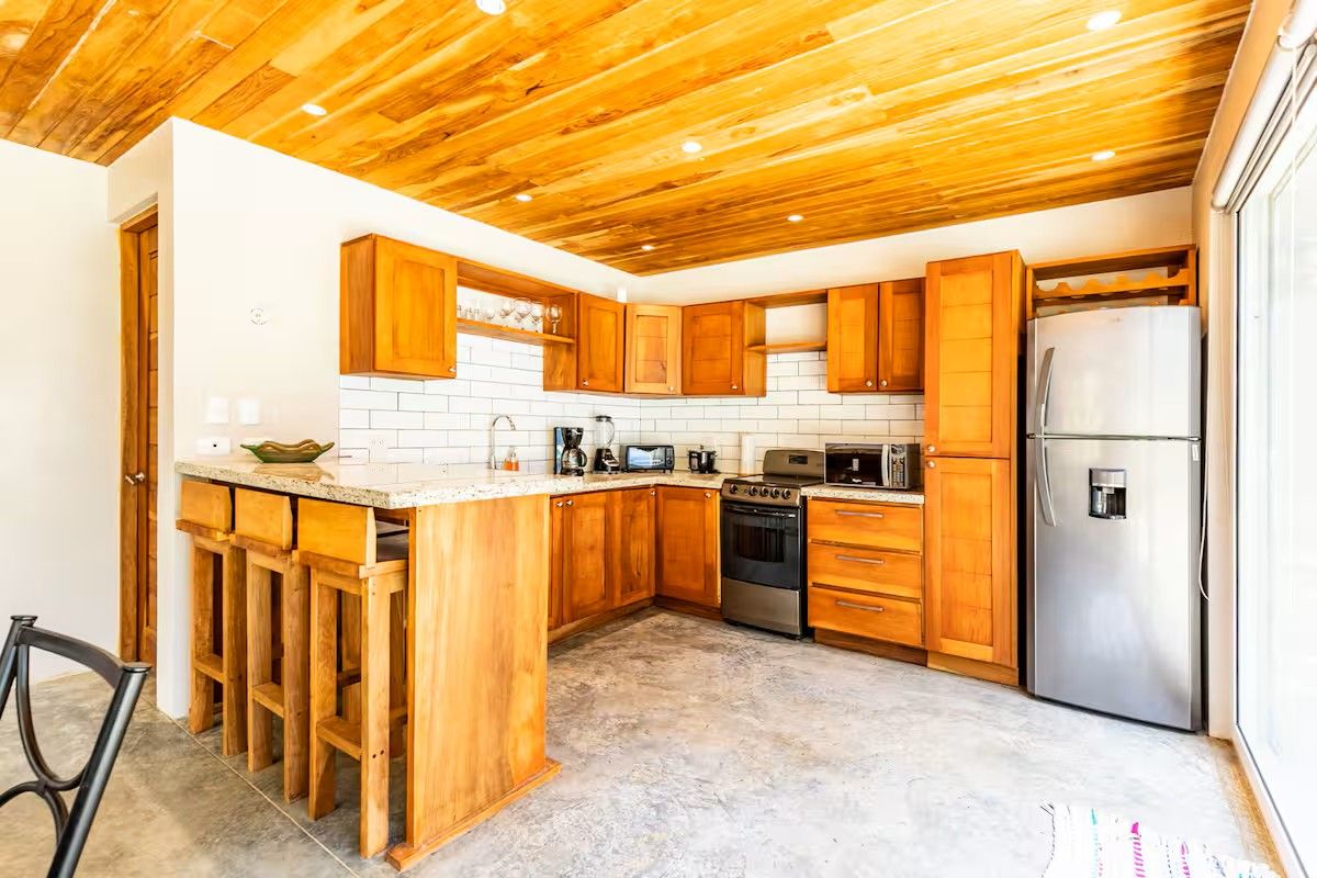 Una cucina con mobili in legno, un frigorifero in acciaio inossidabile e un forno integrato.