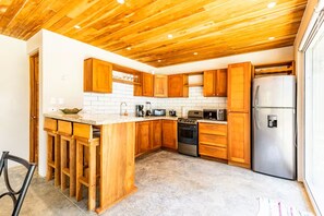 A kitchen with wooden cabinets, a stainless steel refrigerator, and a built-in oven. - Fully equipped house 5 minutes from the beach. Perfect for families or groups of friends. (Nosara)